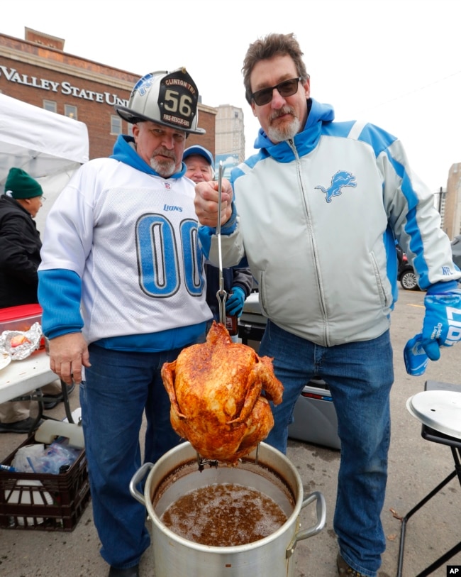 FILE - Paul Cieslak, left, and James Thornton show off their deep fried turkey outside Ford Field before an NFL football game between the Detroit Lions and the Minnesota Vikings, Thursday, Nov. 23, 2017, in Detroit. (AP Photo/Paul Sancya)