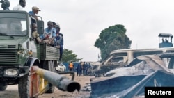 Le personnel de sécurité assis sur un camion surveille les véhicules brûlés lors de l’évasion spectaculaire du chef de la secte Bundu dia Mayala Ne Muanda Nsemi à Kinshasa, République démocratique du Congo, 17 mai 2017.