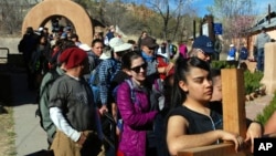 Jasmin Perez, 17, of Espanola, New Mexico, carries a cross on a pilgrimage to a small adobe church in Chimayo, New Mexico, March 30, 2018. She joined thousands of Catholics who traveled by foot to El Santuario de Chimayo in the hills of northern New Mexico in an annual Good Friday pilgrimage that has endured for two centuries. 