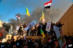 Protesters burn property in front of the U.S. embassy compound, in Baghdad, Iraq, Tuesday, Dec. 31, 2019. Dozens of angry Iraqi Shiite militia supporters broke into the U.S. Embassy compound in Baghdad on Tuesday after smashing a main door and…