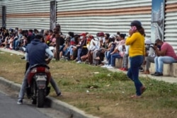 People wearing protective face masks amid the new coronavirus pandemic wait their turn to enter a state-run store in Havana, Cuba, Jan. 14, 2021.
