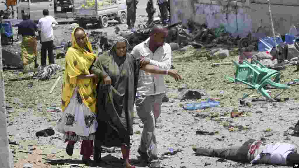 Watu wakimsaidia mwanamke kufuatia mlipuko wa bomu lililotegwa ndani ya gari nje ya jengo la wizara ya elimu Mogadishu.