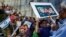 A boy holds a board with the likeness of three teenagers who had been kidnapped in Israel during a memorial service near the United Nations headquarters in New York, June 30, 2014. 