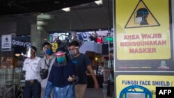 Para pengunjung yang mengenakan masker dan pelindung wajah untuk mencegah penularan Covid-19, keluar dari sebuah pusat perbelanjaan di Surabaya, 3 Juni 2020. (Foto: AFP)