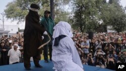 Polisi syariah mencambuk seorang perempuan yang dinyatakan bersalah karena melakukan pelacuran di depan umum di luar sebuah masjid di Banda Aceh, 20 April 2018.