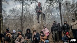 Migrants wait near a buffer zone at the Turkey-Greece border, at Pazarkule, in Edirne district, Feb. 29, 2020. Thousands of migrants stuck on the border clashed with Greek police Saturday, according to an AFP photographer at the scene.