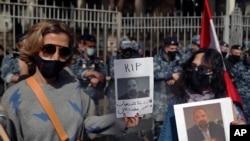 Anti-Hezbollah protesters hold pictures of Lokman Slim, a longtime Shiite political activist and researcher, who has been found dead in his car, during a protest in front of the Justice Palace in Beirut, Lebanon, Thursday, Feb. 4, 2021.