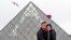 Sepasang turis AS mengambil swafoto di depan Piramida Louvre, Paris. (AP/Remy de la Mauviniere)