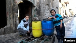 FILE - Boys are pictured beside a cart they use to carry water back to their home in the east Aleppo neighborhood of al-Mashatiyeh, Syria, in this handout picture provided by UNHCR, Jan. 4, 2017. 