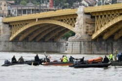 FILE - Rescuers in boats work to prepare to recover a capsized boat under Margaret Bridge in Budapest, Hungary, May 30, 2019.