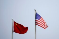 FILE - Chinese and U.S. flags flutter outside a company building in Shanghai, China April 14, 2021.