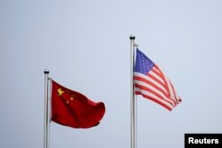 FILE - Chinese and U.S. flags flutter outside a company building in Shanghai, China April 14, 2021.