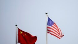 FILE - Chinese and U.S. flags flutter outside a company building in Shanghai, China April 14, 2021.