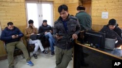 Para jurnalis di Kashmir mengunakan ponsel untuk menjelajah internet di pusat media yang dibuat pemerintah di Srinagar, wilayah Kashmir yang dikuasai India, Januari 2020.