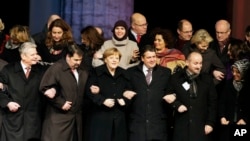 German Chancellor Angela Merkel, front third from left, attends a vigil organized by the German Muslim Council to commemorate the victims of last week's Paris terror attacks in front of the Brandenburg Gate near the French embassy in Berlin, Jan. 13, 2015