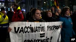 A protestor holds a banner during a small anti-COVID restriction demonstration in the Hague, the Netherlands, Saturday, Dec. 18, 2021.