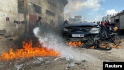 Seorang petugas sedang memadamkan mobil yang terbakar akibat serangan Israel, di tengah konflik yang sedang berlangsung antara Israel dan Hamas, di Rafah di selatan Jalur Gaza, 10 Februari 2024. (Foto: REUTERS/Bassam Masoud)