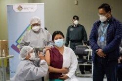 El presidente de Bolivia, Luis Arce, observa a un trabajador de la salud que recibe una dosis de la vacuna Sputnik V, en el Hospital del Norte en El Alto, en las afueras de La Paz, Bolivia, enero 30 de 2021.