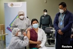 El presidente de Bolivia, Luis Arce, observa a un trabajador de la salud que recibe una dosis de la vacuna Sputnik V, en el Hospital del Norte en El Alto, en las afueras de La Paz, Bolivia, enero 30 de 2021.