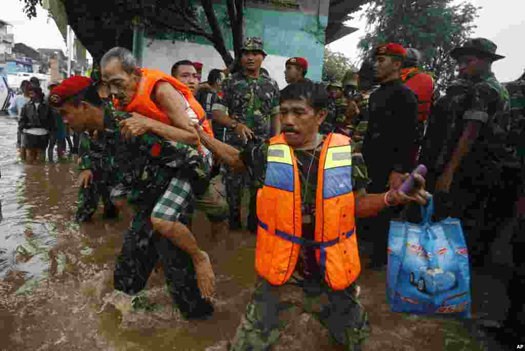 An Indonesian soldier helps evacuate an old man in a flooded street in Jakarta. Flood waters were gradually receding from the main streets of the teeming capital city on Friday. 