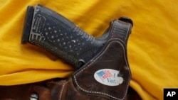 FILE - A man wears an unloaded pistol during a pro gun-rights rally in Austin, Texas, April 14, 2018. 