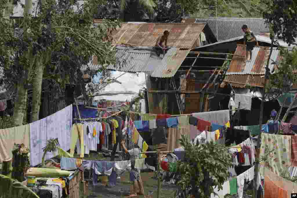 A family goes on their daily business Thursday, July 17, 2014, a day after Typhoon Rammasun hit Batangas city, Philippines.