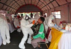 Seorang pria bereaksi saat petugas kesehatan mengambil sampel usap hidungnya saat tes massal untuk virus corona baru di Tangerang, Indonesia, Kamis, 21 Juli 2020. (Foto: AP/Tatan Syuflana)