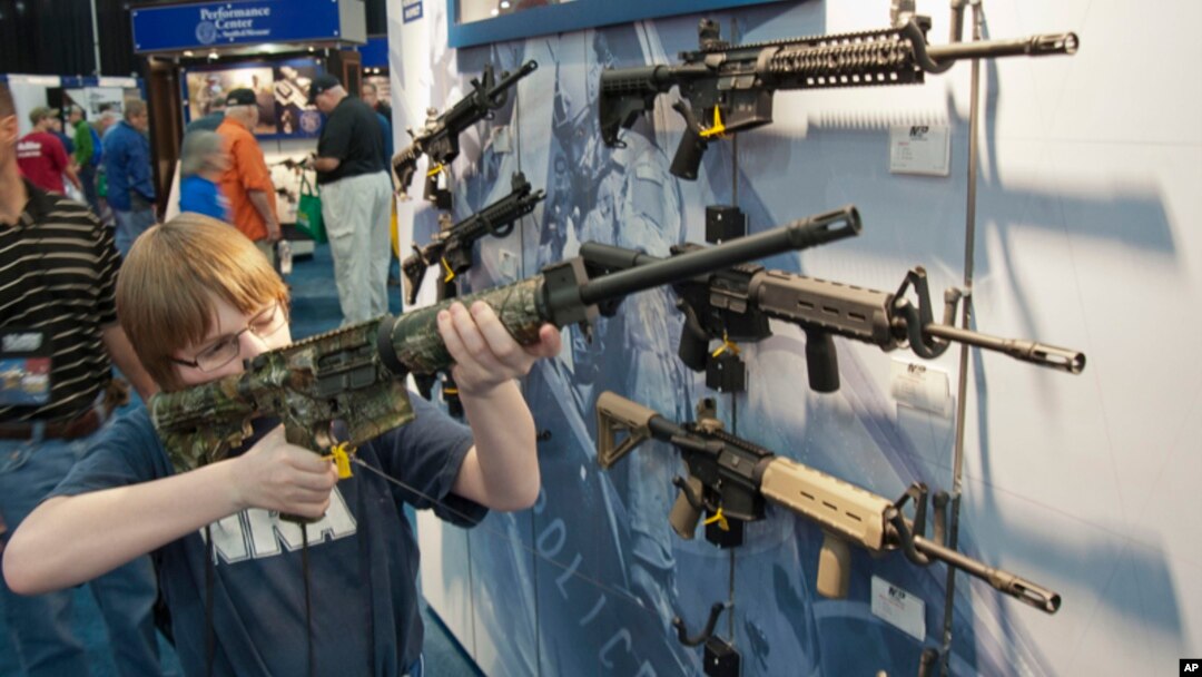 Un jovencito apunta con un fusil de asalto durante la convención anual de la NRA el fin de semana en Houston.