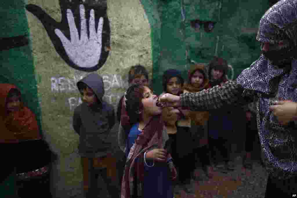 Murid sekolah Pakistan, yang harus meninggalkan rumah di wilayah timur laut bersama keluarganya konflik antara kelompok militan dan tentara pemerintah, mendapat vaksin polio dari petugas kesehatan di pinggir kota Islamabad (31/1). (AP/Muhammad Muheisen)