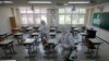 Health officials wearing protective gear spray disinfectant to help reduce the spread of the new coronavirus in a class at a high school in Seoul, South Korea, May 11, 2020.