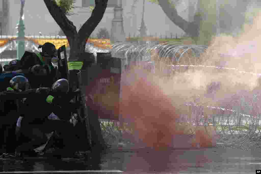 Riot police launch tear gas to protesters marching to Government House in Bangkok, Thailand.