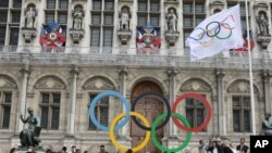 FILE: Paris mayor Anne Hidalgo helps raise the Olympic flag outside the Paris Town Hall, Monday, Aug.9, 2021 during an event to mark the arrival of the flag. 