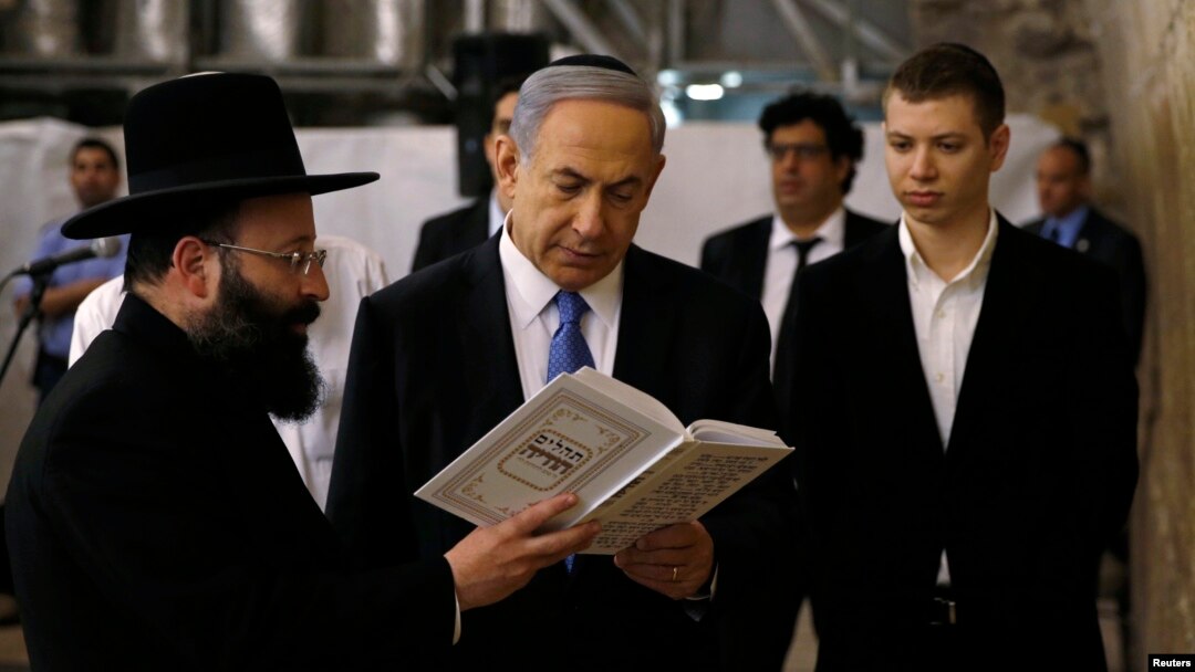 FILE - Israel's Prime Minister Benjamin Netanyahu, center, reads a prayer with Western Wall Rabbi Shmuel Rabinowitz, left, as his son Yair, right, stands next to him, at the Western Wall, in Jerusalem's Old City, March 18, 2015.