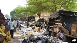 Residents look at debris on the pavement on April 16, 2011 in Ouagadougou after soldiers from three barracks took to the streets of the Burkina Faso capital overnight, firing into the air and pillaging as a mutiny entered its third day