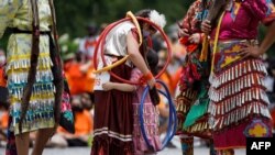 FILE - Hoop dancer Emilee Ann, left, hugs Ayiana Myran as they wait to perform during the Every Child Matters walk in honor of children who died in Canada's Residential School system, in Toronto, Canada, July 6, 2021.