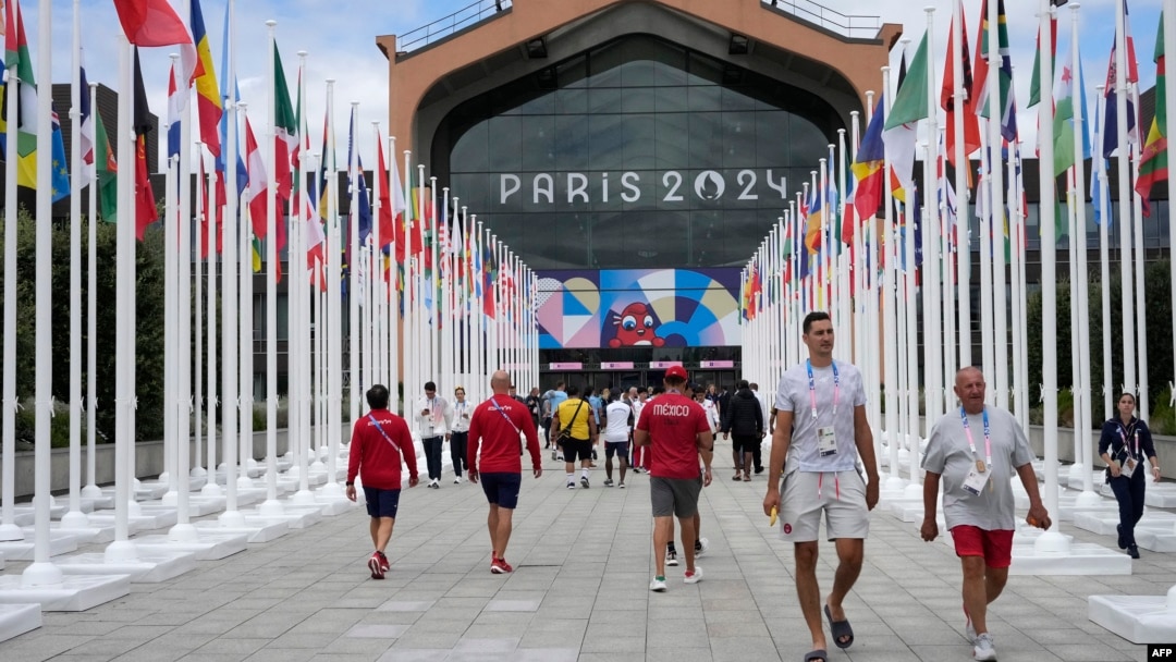 Los participantes de los Juegos Olímpicos y Paralímpicos de París 2024 caminan frente a la cafetería de la Villa Olímpica, en Saint-Denis, al norte de París, el 22 de julio de 2024, antes de la ceremonia de apertura de los Juegos Olímpicos y Paralímpicos de París 2024.
