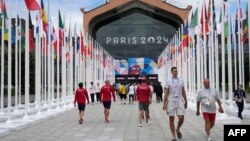 Los participantes de los Juegos Olímpicos y Paralímpicos de París 2024 caminan frente a la cafetería de la Villa Olímpica, en Saint-Denis, al norte de París, el 22 de julio de 2024, antes de la ceremonia de apertura de los Juegos Olímpicos y Paralímpicos de París 2024.