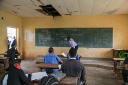 FILE - A teacher wearing a face mask to protect against the coronavirus writes on a blackboard at the Technical High School of Nkol-Bisson in Yaounde, Cameroon, June 1, 2020.