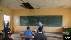 FILE - A teacher wearing a face mask to protect against the coronavirus writes on a blackboard at the Technical High School of Nkol-Bisson in Yaounde, Cameroon, June 1, 2020. 