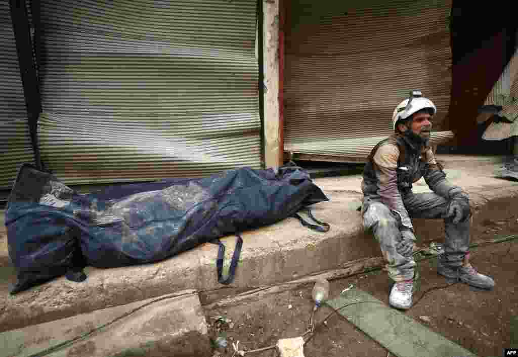 A member of the White Helmets sits next to a body bag containing a victim removed from the rubble of a building, hit during an airstrike by pro-regime forces on the rebel-held town of Ariha in the northern countryside of Syria&#39;s Idlib province.