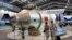 FILE - Visitors sit beside a model of Chinese-made Tiangong 1 space station at the 8th China International Aviation and Aerospace Exhibition, known as Airshow China 2010, in Zhuhai city, south China, Guangdong province, Nov. 16, 2010. 