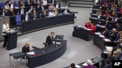 German Chancellor Angela Merkel, left, addresses lawmakers on the decisions of the EU summit at the parliament Bundestag in Berlin, June 29, 2012.