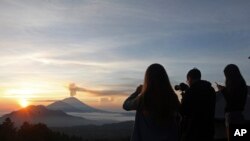 Wisatawan mengambil foto Gunung Agung pada saat matahari terbit di Kintamani, Bali, 13 Desember 2017.(AP Photo/Firdia Lisnawati)