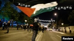 A demonstrator waves a Palestinian flag during a protest against Donald Trump's decision to recognize Jerusalem as the capital of Israel, in Athens, Greece, Dec. 8, 2017. 