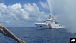 FILE - A Chinese Coast Guard boat approaches a Filipino fishing vessel off Scarborough Shoal in the South China Sea, Sept. 23, 2015.