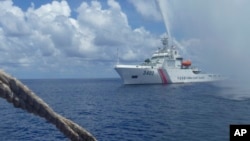 FILE - A Chinese Coast Guard vessel approaches a Filipino fishing boat off Scarborough Shoal in the South China Sea, Sept. 23, 2015.