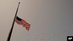 FILE - An American flag flies at half-staff.