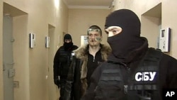 A Russian Channel One undated television grab shows a man identified as Adam Osmayev (C), one of the suspected militants conspiring to kill Vladimir Putin, walking under escort of the masked agents of the Ukrainian Security Service (SBU), shortly after hi