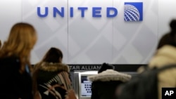 FILE- People stand in line at a United Airlines counter at LaGuardia Airport in New York, March 15, 2017. A dog died on a United Airlines flight from Houston to New York after a flight attendant ordered its owner to put the animal's carrier in the plane's overhead bin.