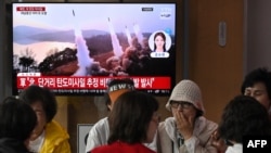 Люди перед телеэкраном, по которому показывают выпуск новостей с кадрами северокорейских ракетных испытаний. Сеул, 30 мая 2024 года.